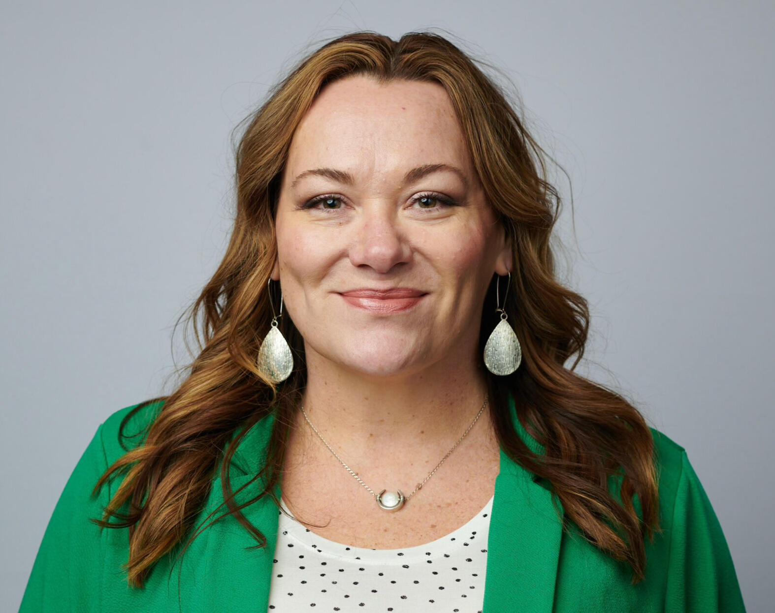 Jennifer Fish photograph of white woman with long brown hair, wearing a green blazer